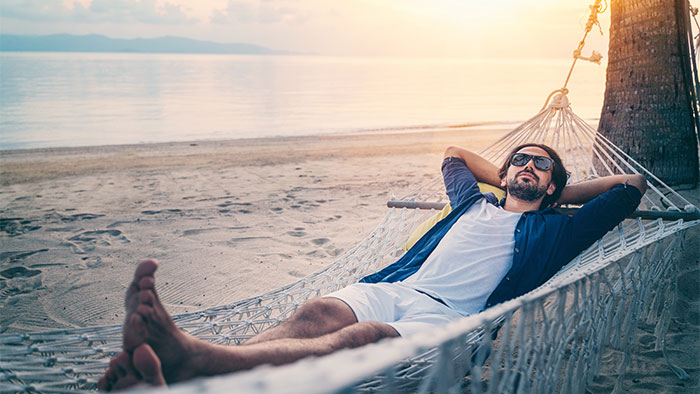 Dude relaxing o n a beach in a hammock